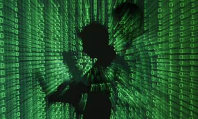 Een afbeelding toont de projectie van binaire code op een man met een aptop-computer in Warschau